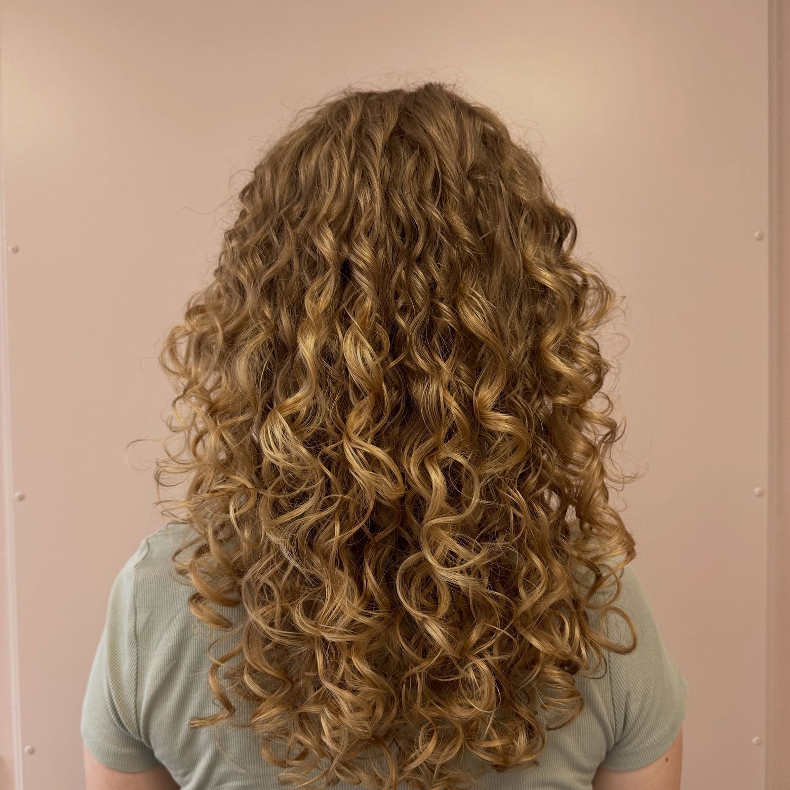Gedefinieerde goudblonde krullen van achteren, geknipt bij Kapsalon Marlies