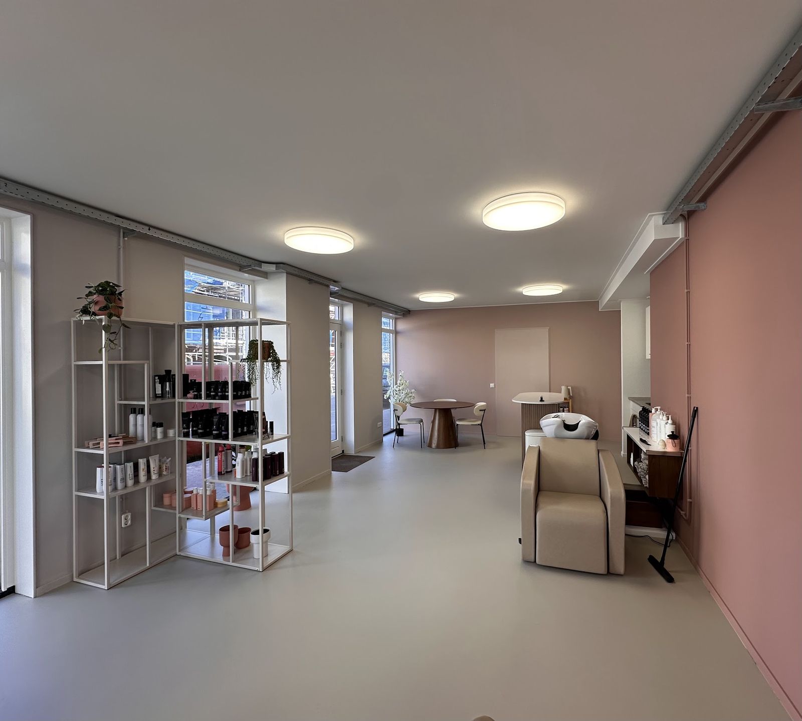 De nieuwe salon aan de Oude Koemarkt: witte kasten met producten, een wasstoel en een roze wand